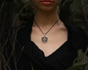 Person wearing a Hecate necklace with a decorative pendant against a dark background