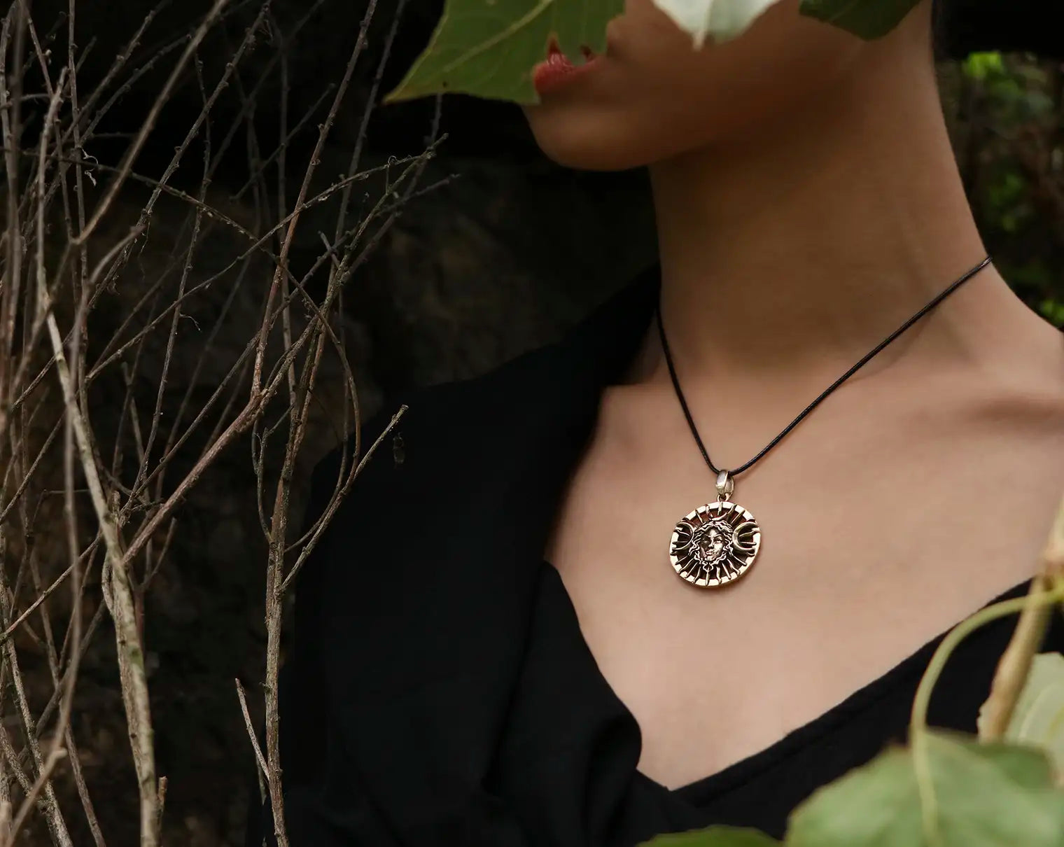 Person wearing a necklace with a circular pendant Hecate  in a natural setting