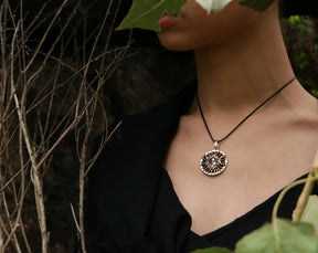 Person wearing a necklace with a circular pendant Hecate  in a natural setting