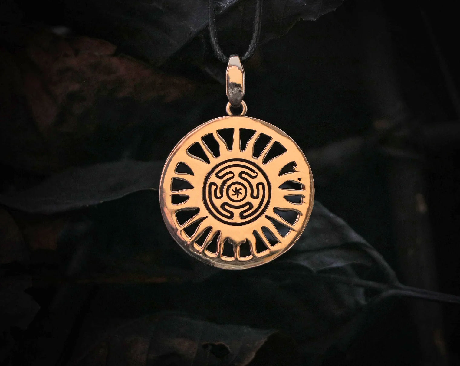 Back side of Hecate Bronze pendant with intricate design on a dark background