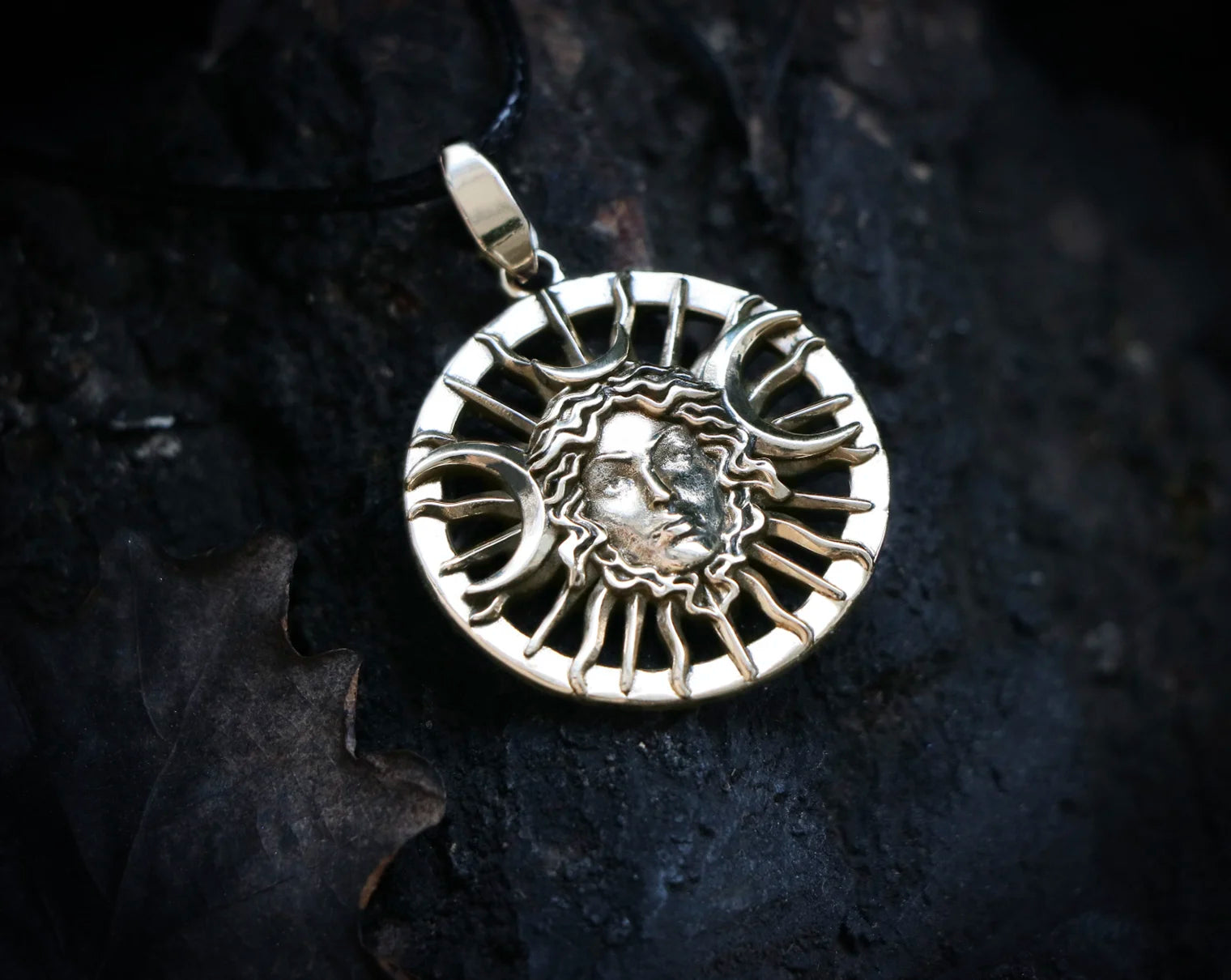 Silver Hecate Goddess pendant with a face design on a dark textured background