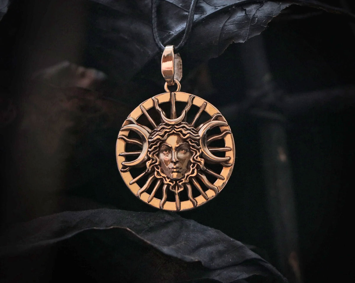 Bronze Hecate Goddess pendant with face design  and triple moon on a dark background