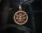 Bronze Hecate Goddess pendant with face design  and triple moon on a dark background