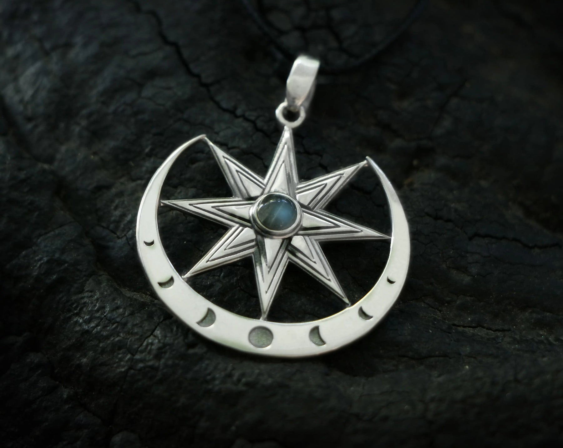 Silver Inanna pendant with star design and central moonstone gem on a dark textured background
