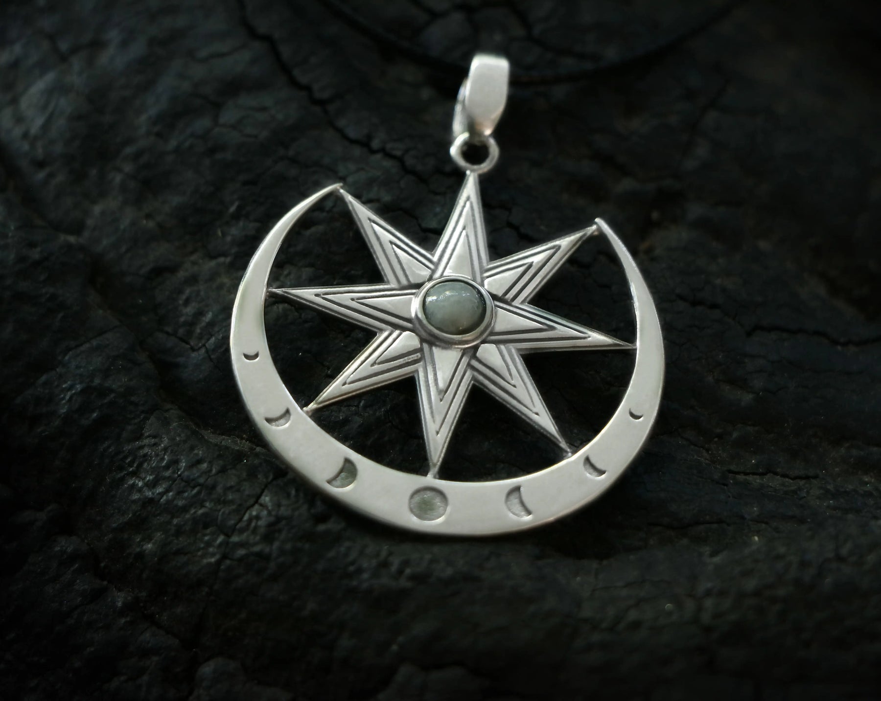 Silver Ishtar pendant with eight pointed star design and moonstone gem on a dark textured background