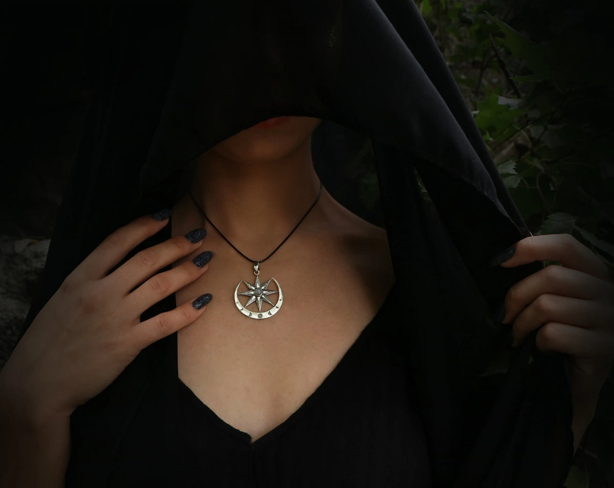 Person wearing a black hooded garment with a Inanna necklace featuring a moonstone
