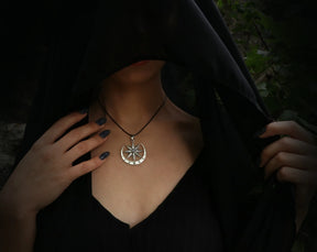 Person wearing a black hooded garment with a Inanna necklace featuring a moonstone