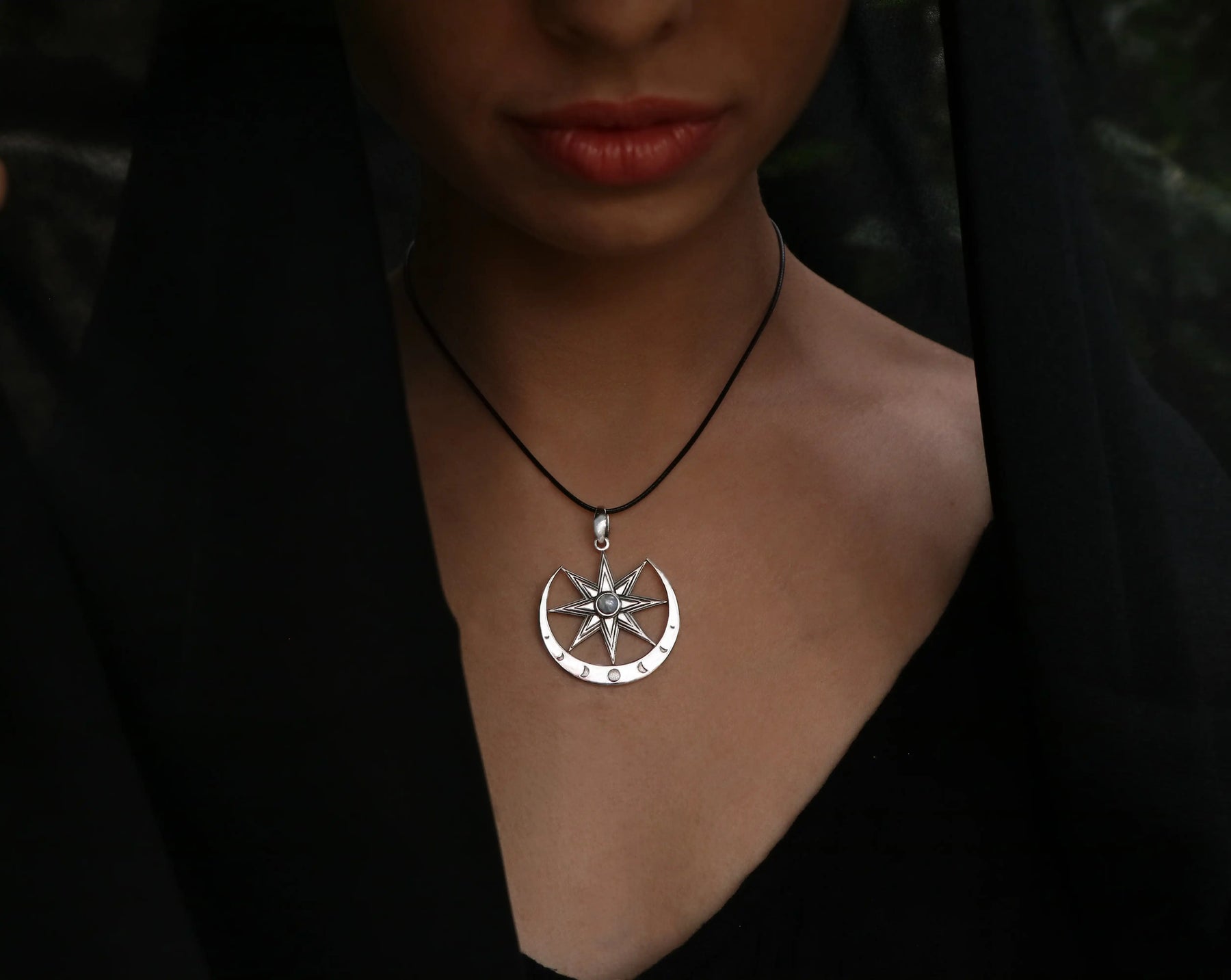 Silver Ishtar necklace with a eight pointed star pendant on a person wearing a black outfit.