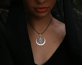 Silver Ishtar necklace with a eight pointed star pendant on a person wearing a black outfit.