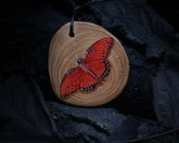 May include: A wooden pendant with a hand-painted red butterfly. The pendant is on a black cord and has the text "Top Secret" written on it.