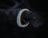 May include: A silver ring with a blue and yellow gemstone band.