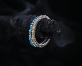 May include: A silver ring with a blue and yellow gemstone band.