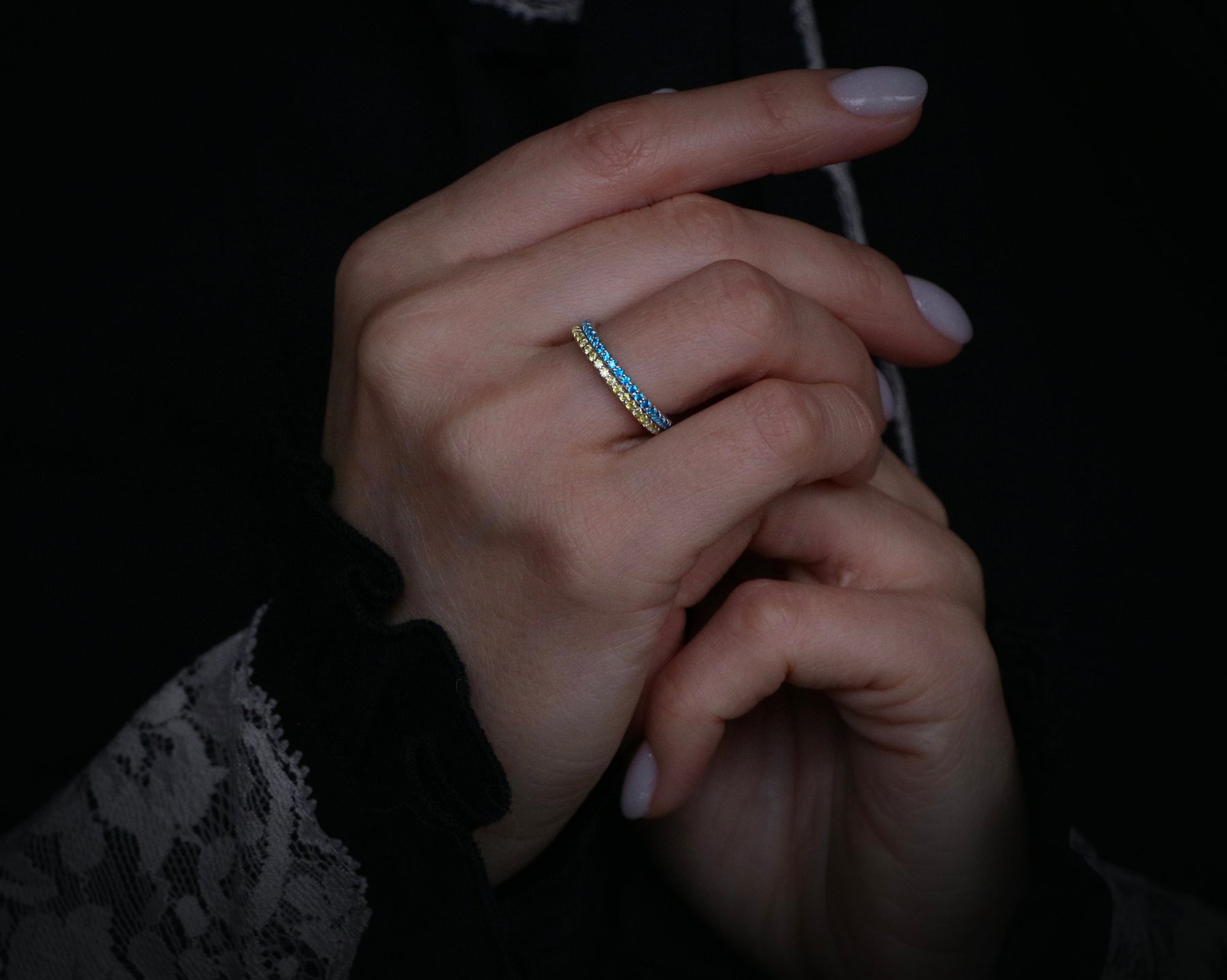 May include: A gold and blue ring with a textured design. The ring is worn on a finger.