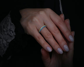 May include: A gold band ring with a double row of blue and yellow gemstones.