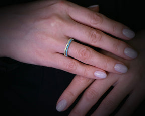 May include: A gold and blue eternity band ring with small gemstones set in a continuous line.