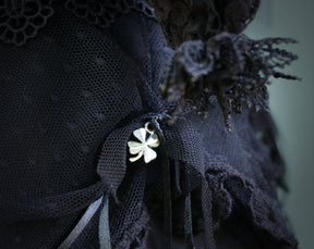May include: A black lace fabric with a gold four-leaf clover charm attached.