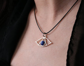 May include: A silver necklace with a pendant shaped like an eye. The eye has a blue gemstone in the center.