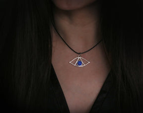 May include: A silver necklace with a blue gemstone eye pendant. The pendant is in the shape of an eye with a triangle inside.