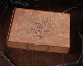 May include: A wooden box with a laser-engraved design featuring the words "Pagan Workshop" inside a triangle with a sunburst pattern.