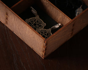 May include: Two silver earrings with a geometric design in a wooden box with compartments. The earrings feature a pentagram with a tree of life design.