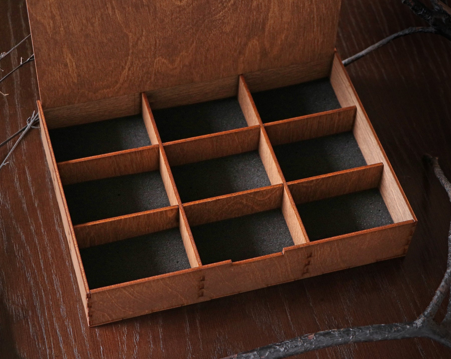 May include: A wooden box with a hinged lid and a compartmentalized interior. The box is made of light brown wood and has a natural finish. The interior of the box is lined with black felt.
