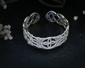 May include: A silver openwork cuff bracelet with a delicate, intricate design.