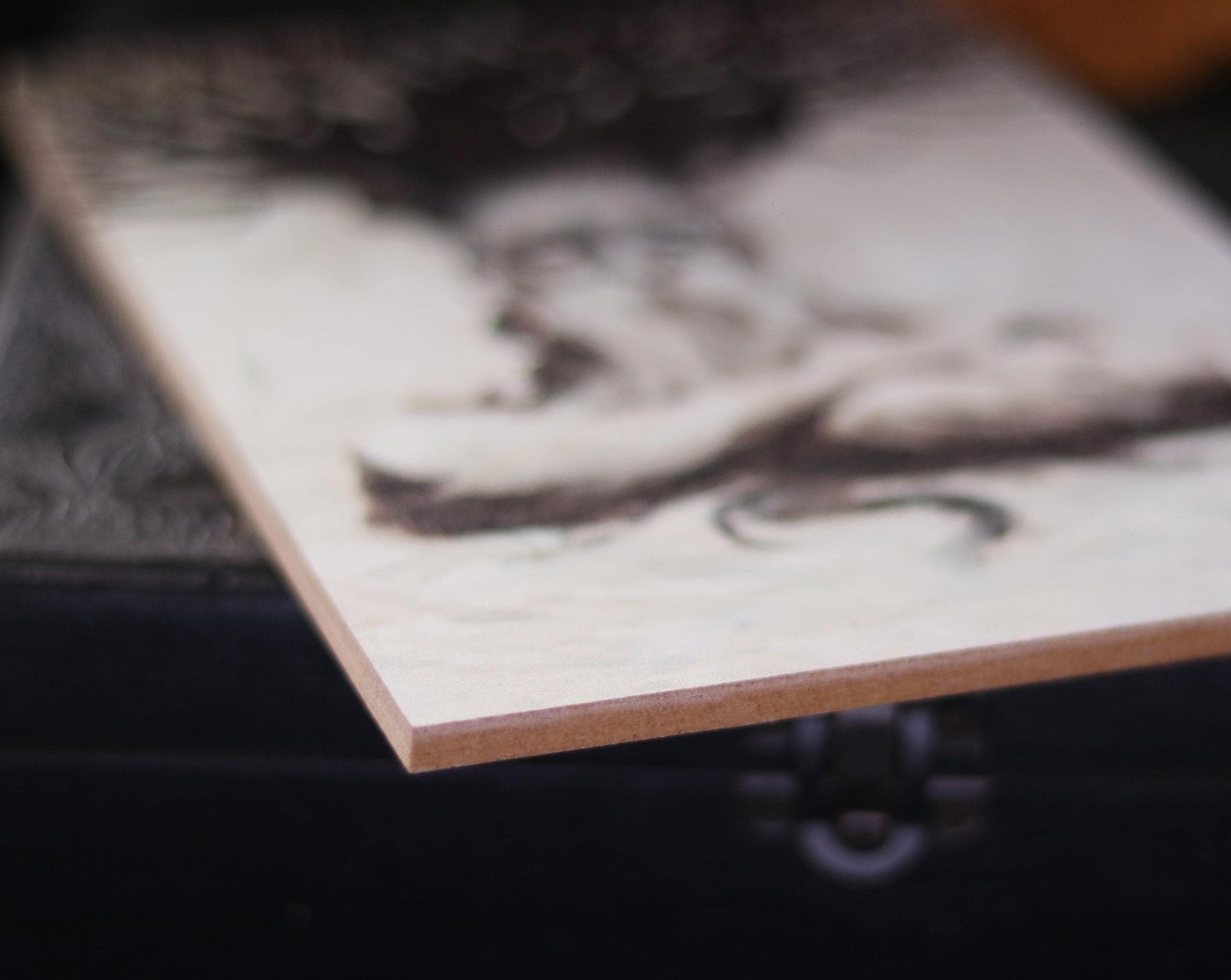 May include: A close-up of a wooden plaque with a light brown background and a black and white abstract design.