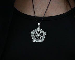 May include: A silver pendant necklace with a five-pointed star design. The star is surrounded by five smaller symbols, each representing a different element. The necklace is on a black cord.