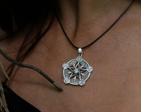 May include: A silver pendant necklace with a five-pointed star design. The star is surrounded by a circle of smaller symbols and a central stone.