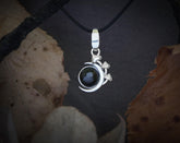 May include: A silver crescent moon pendant with a black gemstone in the center. The pendant is adorned with three small silver flowers.