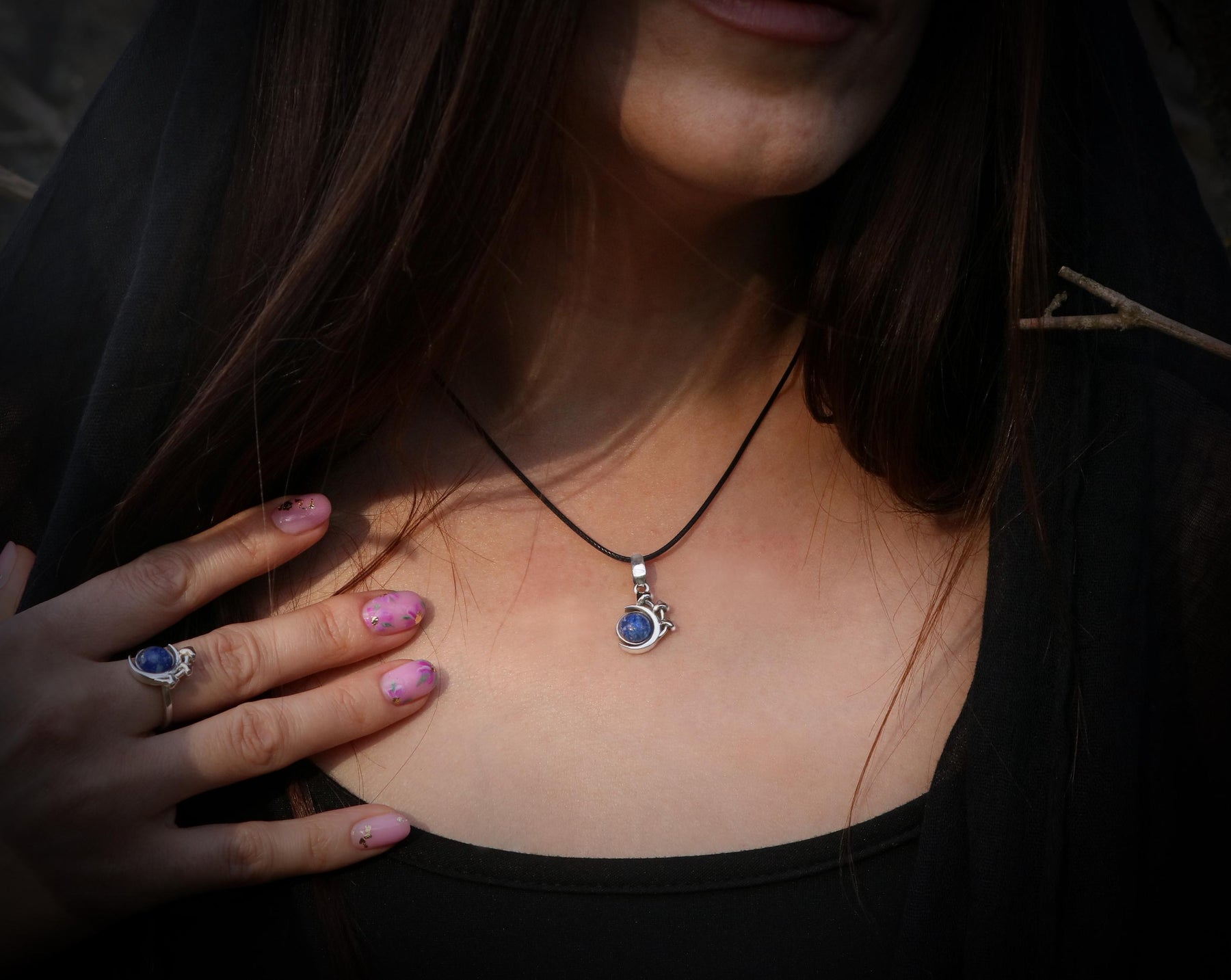 May include: A silver necklace with a blue gemstone pendant in the shape of a crescent moon.