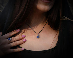 May include: A silver necklace with a blue gemstone pendant in the shape of a crescent moon.
