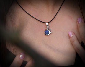 May include: A silver necklace with a blue gemstone pendant. The pendant is shaped like a crescent moon with a small star design.