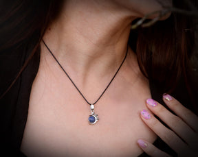 May include: A silver necklace with a blue gemstone pendant. The pendant is shaped like a crescent moon with a small crown on top.