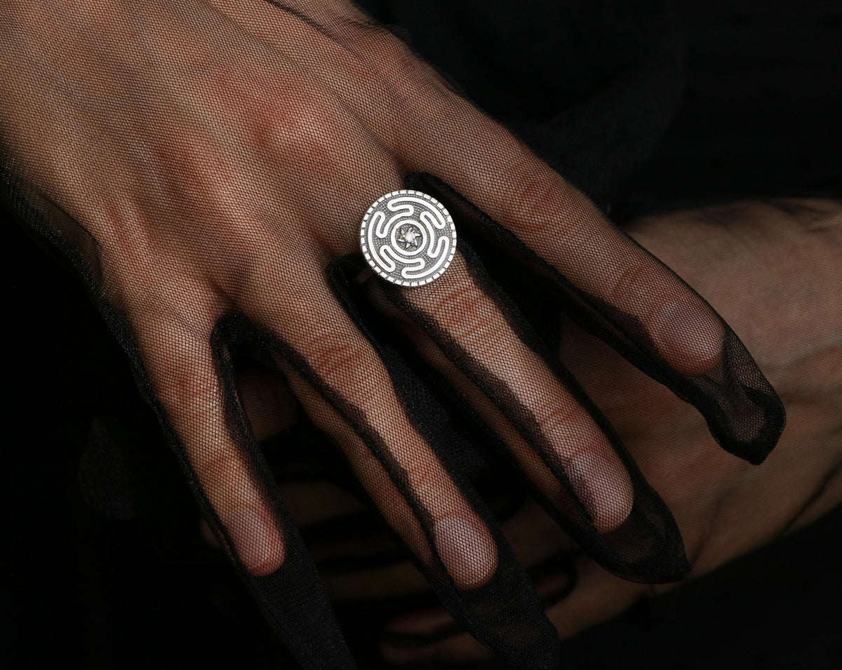 Sterling silver Hecate ring on a hand in a black mesh glove. Adjustable occult jewelry featuring the Strophalos of Hekate.