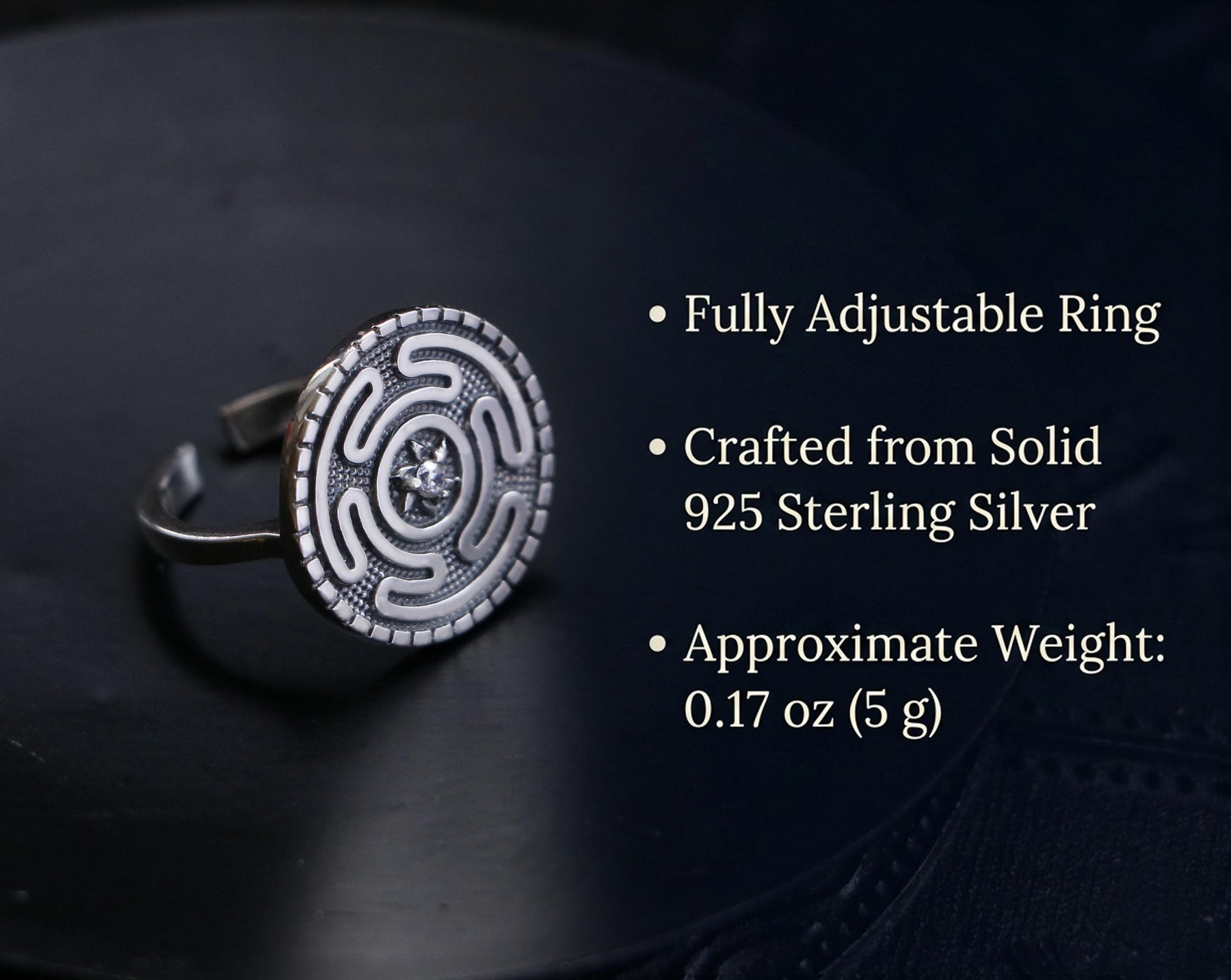 May include: A sterling silver adjustable ring with a circular design. The ring features a detailed pattern and a small, central gemstone. The text on the image says it is crafted from solid 925 sterling silver and weighs approximately 0.17 oz.
