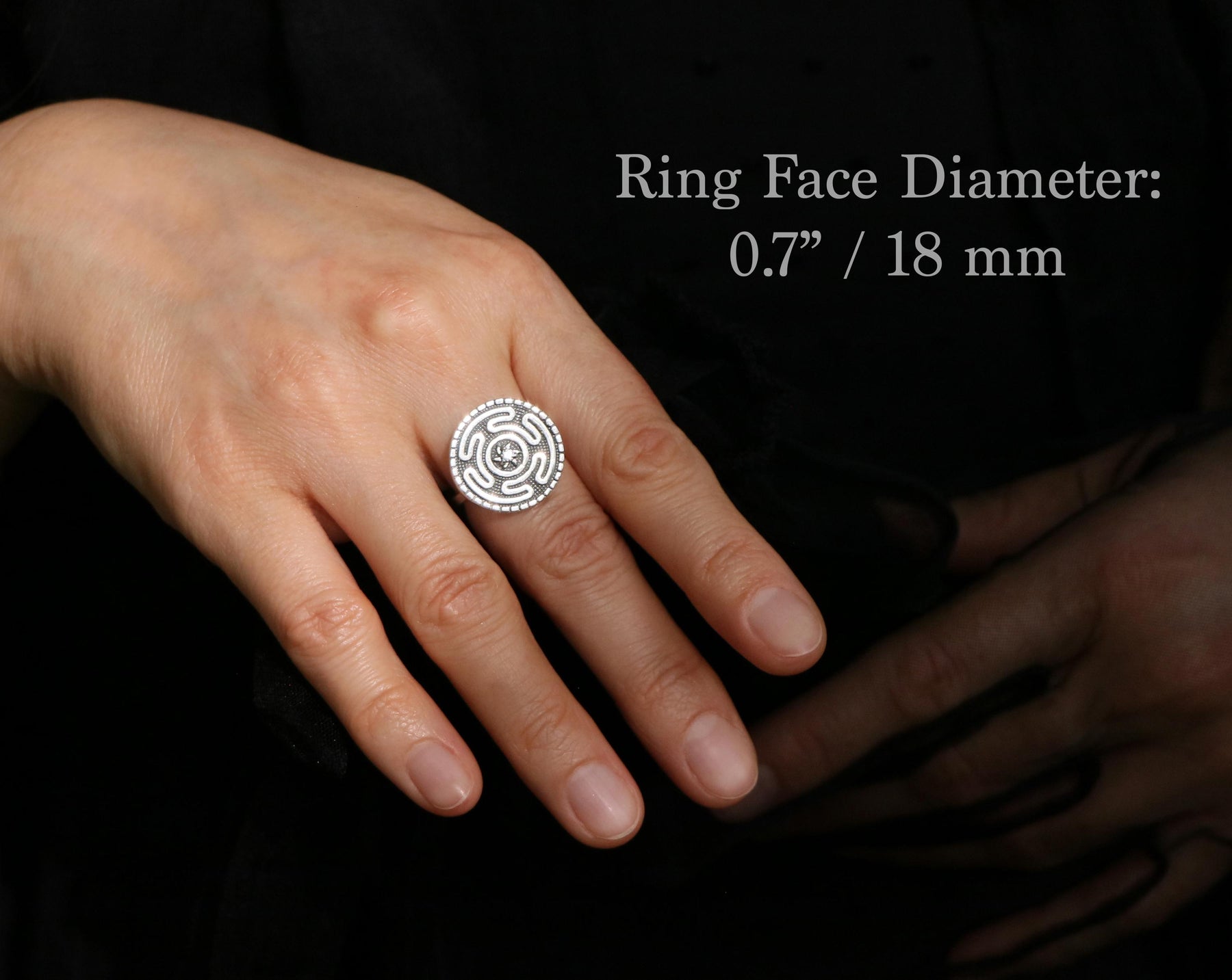 May include: A silver ring with a circular face featuring a maze-like design and a central starburst. The ring face diameter is 0.7 inches (18 mm). The ring is on a hand against a dark background.