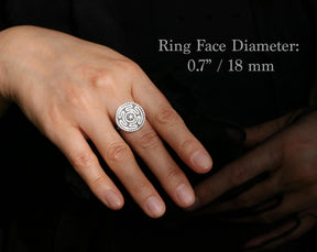 May include: A silver ring with a circular face featuring a maze-like design and a central starburst. The ring face diameter is 0.7 inches (18 mm). The ring is on a hand against a dark background.