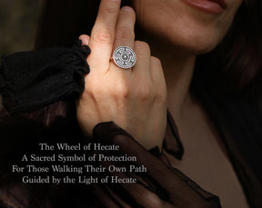 May include: A silver ring featuring a circular design with a maze-like pattern and a central stone. The ring is worn on a finger. The text on the image reads: "The Wheel of Hecate, A Sacred Symbol of Protection, For Those Walking Their Own Path, Guided by the Light of Hecate."