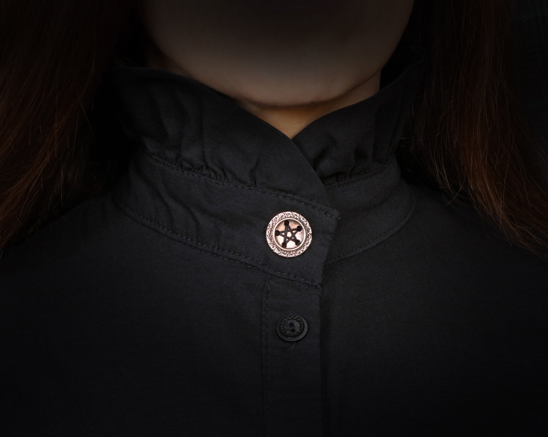 bronze pentagram button sewed on a shirt