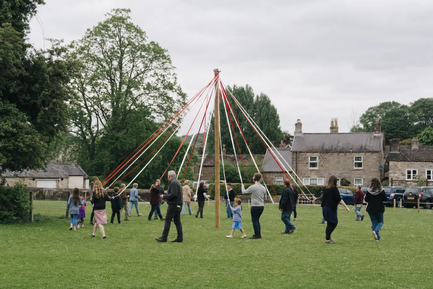 Contemporary rural community dancing around a maypole in spring